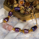 دستبند زنانه شوکا با سنگ رز کوارتز و مروارید بنفش، آویز صلیب طلایی، طراحی دست‌ساز و لوکس.