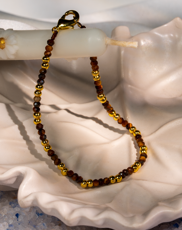 دستبند زنانه شوکا با سنگ چشم‌ببر قهوه‌ای و گوی‌های طلایی، طراحی مینیمال و کلاسیک دارد و مناسب استفاده روزمره و رسمی است.