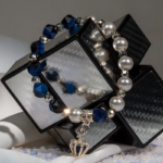 خرید دستبند زنانه شوکا با سنستیک آبی، مروارید سفید و آویز تاج نقرهای، طراحی شیک و دستساز.