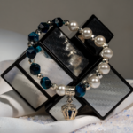 خرید دستبند زنانه شوکا با سنستیک سرمهای، مروارید سفید و آویز تاج نقرهای، طراحی شیک و دستساز.