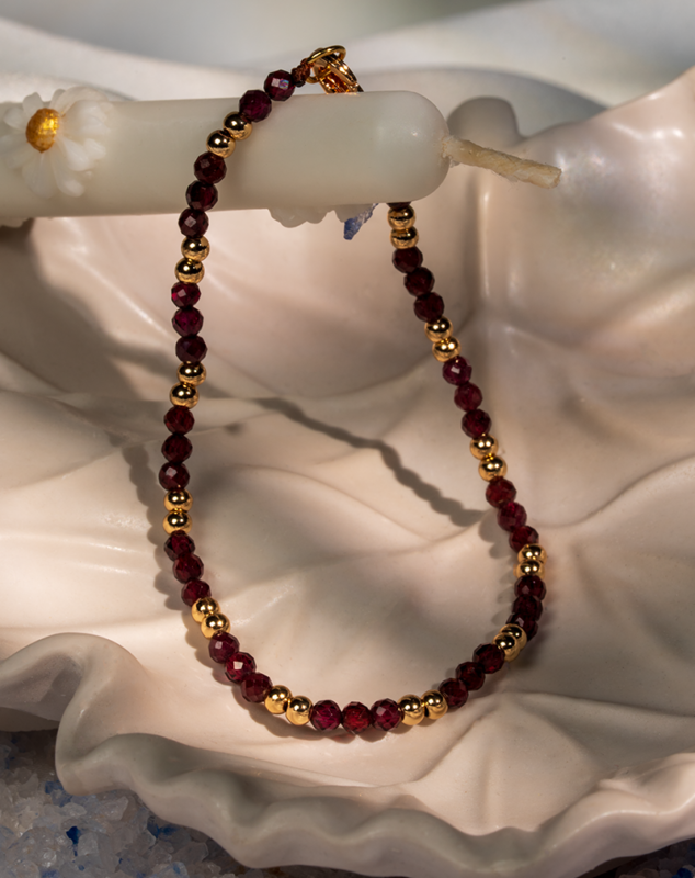 دستبند زنانه شوکا با سنگ گارنت زرشکی و گوی‌های طلایی، مینیمال و لوکس.