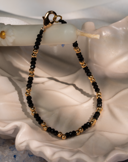 دستبند زنانه شوکا با مهره‌های مشکی تراش‌خورده و گوی‌های طلایی، طراحی مینیمال و کلاسیک دارد. این مدل دست‌ساز، سبک، شیک و مناسب استفاده روزمره و رسمی است.