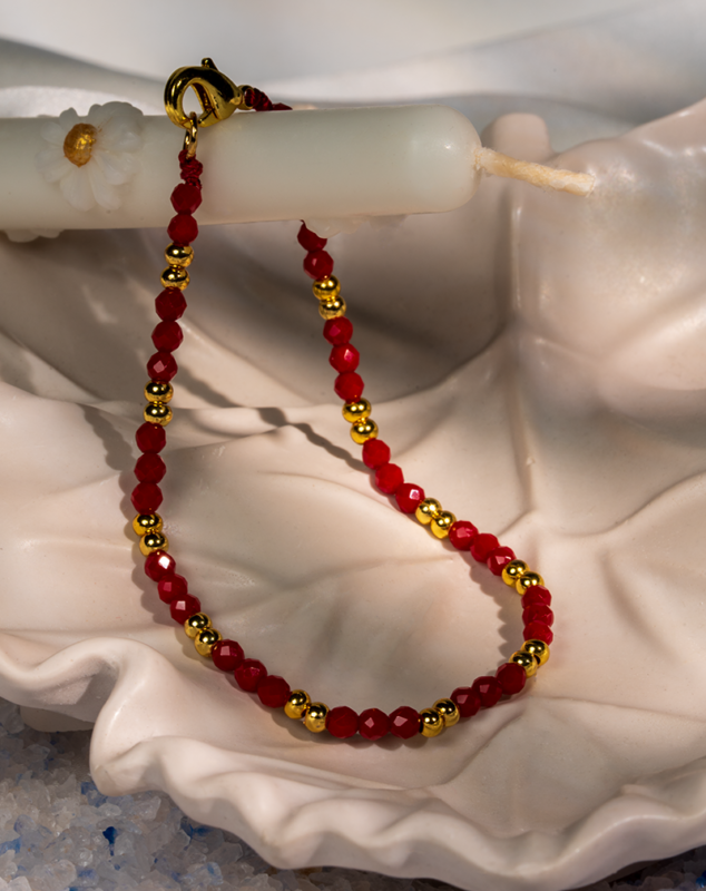 دستبند زنانه شوکا با مهره‌های قرمز و گوی‌های طلایی، طراحی مینیمال و چشم‌گیر دارد و مناسب استایل‌های جسور و خاص است.