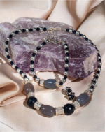 ست زیورآلات زنانه شوکا شامل گردنبند، دستبند و گوشواره با سنگ عقیق طبیعی، گلدستون و مروارید. ترکیب رنگ طوسی و سرمه‌ای با طراحی لوکس و دست‌ساز.