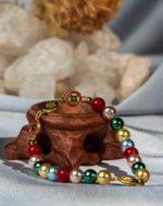 دستبند مروارید رنگین نوجوان شوکا با ترکیب مرواریدهای آبی، سبز، قرمز و کرم در کنار جزئیات طلایی، یک اکسسوری شاد و دوست‌داشتنی برای استایل‌های نوجوانانه است.