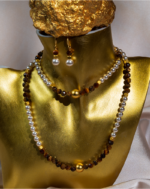 ست زیورآلات زنانه شوکا با ترکیب سنگ طبیعی چشم ببر قهوه‌ای و مروارید سفید. شامل گردنبند، دستبند و گوشواره با طراحی کلاسیک و جزئیات طلایی.